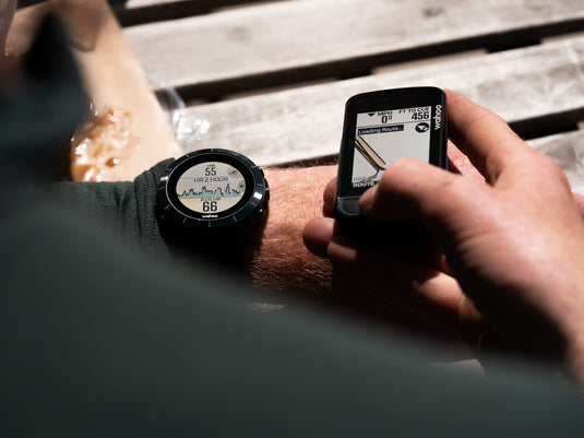 Cyclist syncing Wahoo ELEMNT Bolt V2 GPS Bike Computer with Wahoo fitness watch for route navigation.