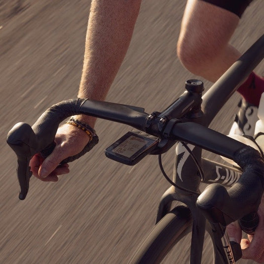 Cyclist riding a road bike with Wahoo ELEMNT ROAM v2 GPS bike computer mounted on the handlebars.