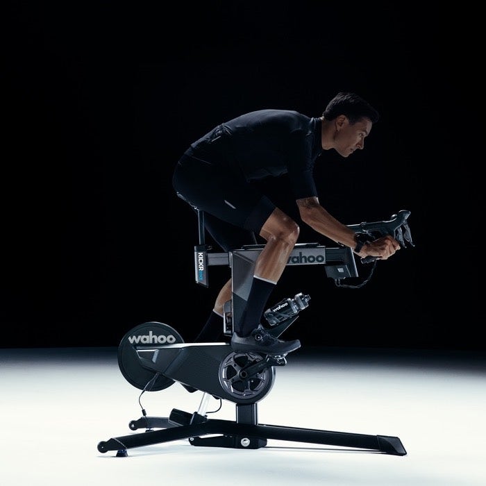 Chargez l&#39;image dans la visionneuse de la galerie, Cyclist riding Wahoo KICKR BIKE V2 Smart Bike with real-time grade changes and customizable gearing
